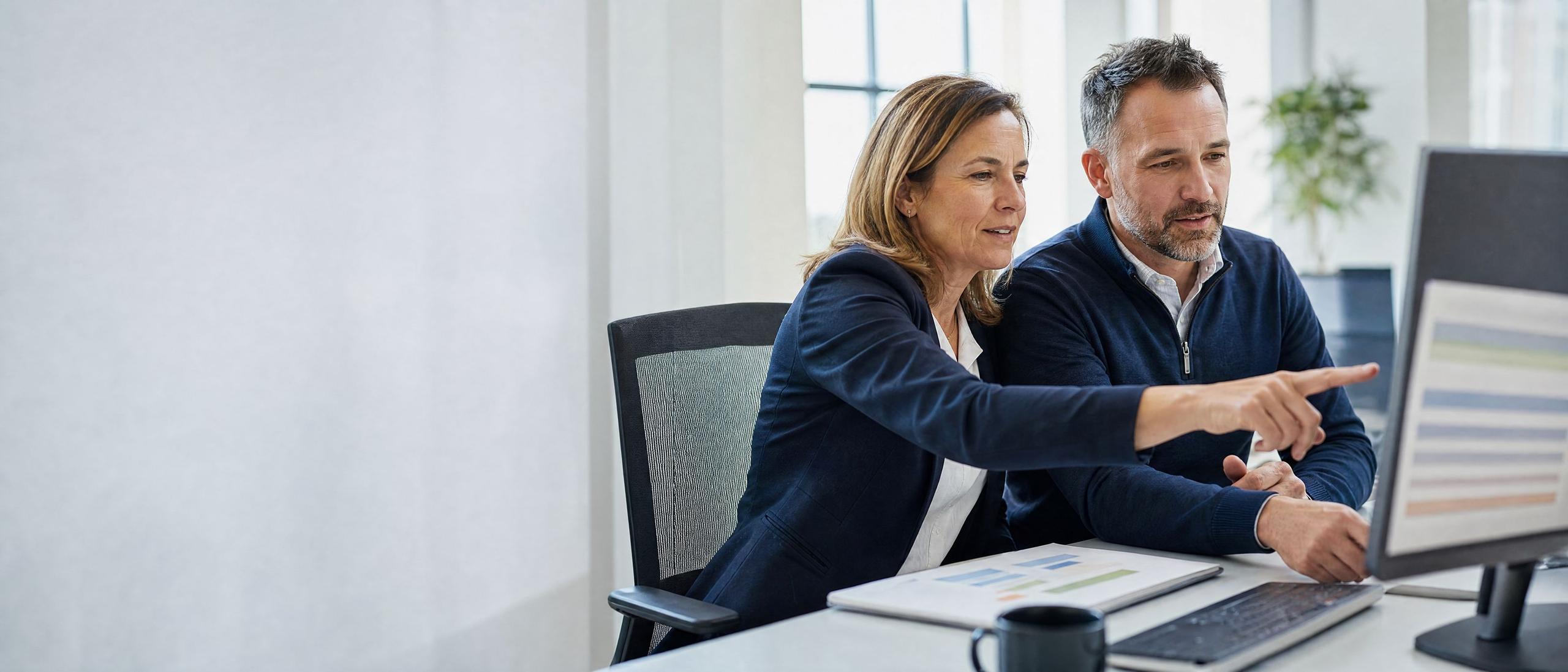 A security analyst and a practice operations leader review a prioritized list of findings together on a large monitor.
